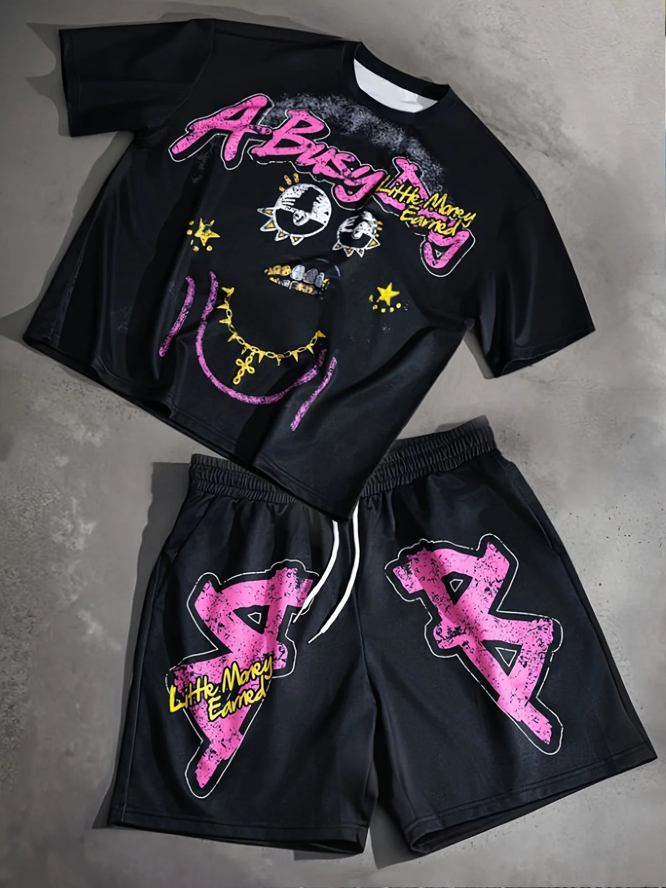 Black t-shirt and shorts set with pink and yellow graphics on a gray surface