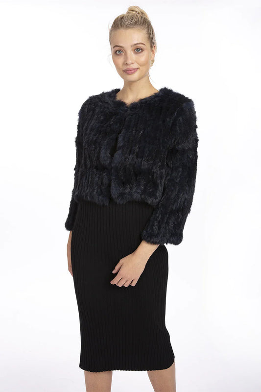 Woman wearing a black fur jacket over a black dress on a white background