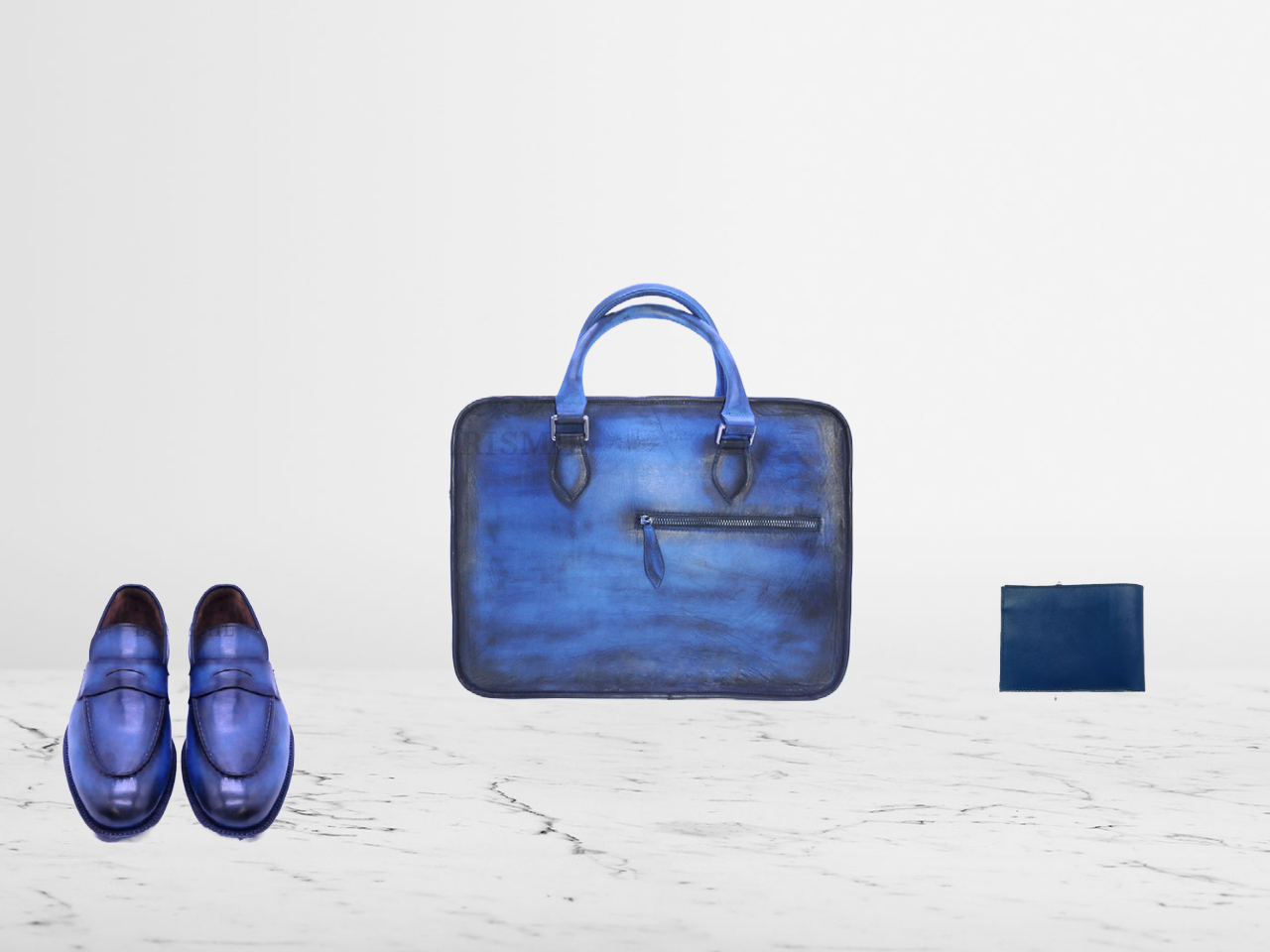 Men's blue leather gift set featuring a handcrafted leather briefcase, matching dress loafers, and coordinating wallet on a white marble surface.