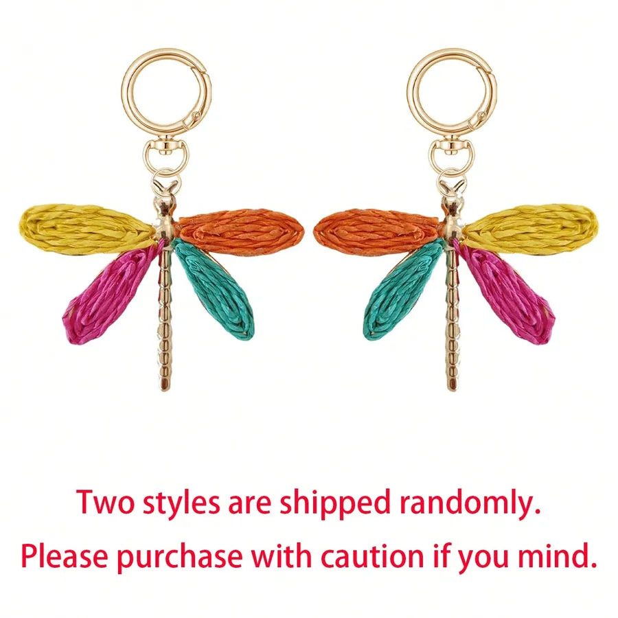 Colorful dragonfly alloy bag charm keychains with woven multicolor wings and gold-tone hardware displayed on a white background. Image notes that one of two dragonfly styles is shipped at random. Perfect as a handbag charm, purse accessory, backpack charm, or decorative keychain.