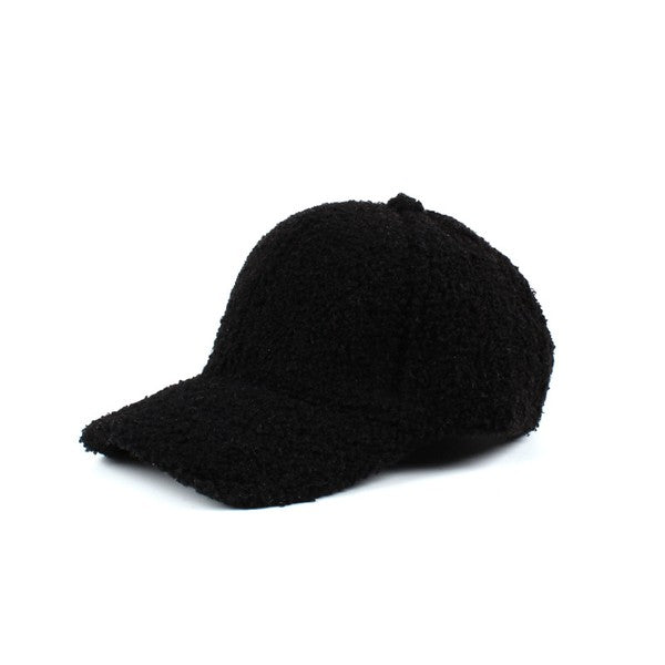 Black boucle sherpa teddy bear knit baseball cap with a curved brim, soft fuzzy fleece texture, six-panel design, and adjustable back closure on a white background.