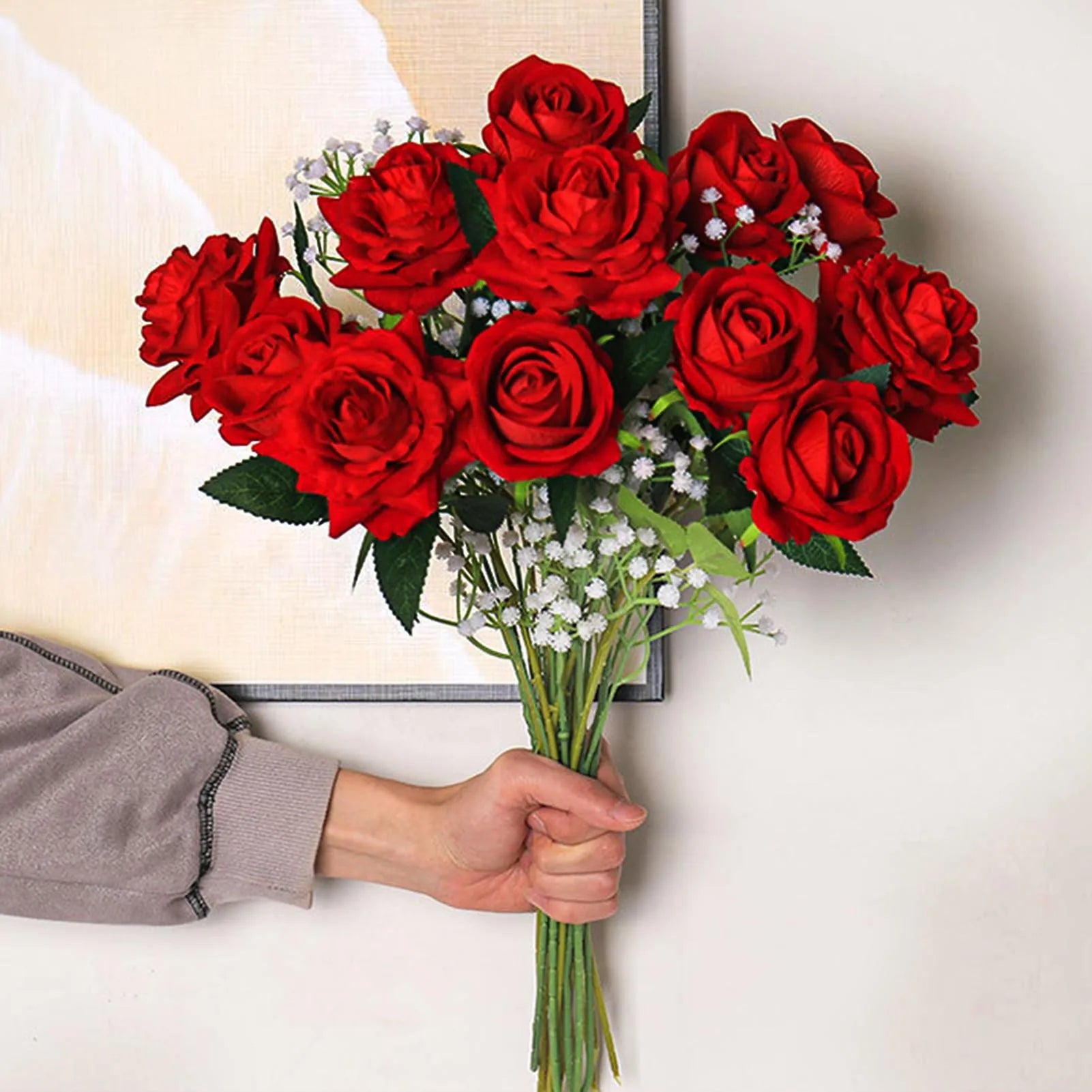 Bouquet of red roses held by a person with a neutral background