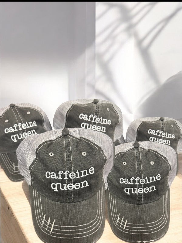 Multiple distressed black and gray mesh trucker hats embroidered with the words "caffeine queen" displayed together on a wooden surface, featuring adjustable Velcro closures and breathable polyester mesh backs. Caffeine Queen Trucker Hat 80% cotton/20% polyester, Herringbone fabric 100% polyester mesh back Velcro closure