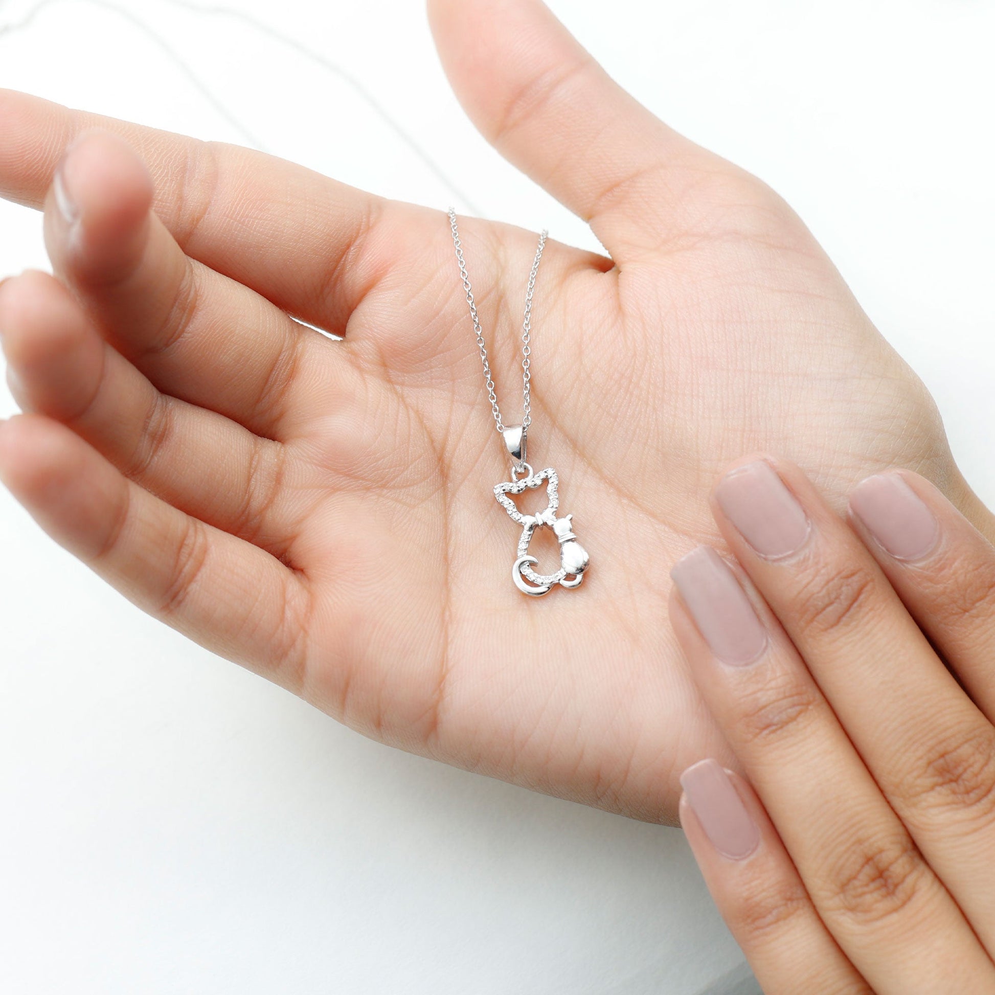 Silver cat-shaped pendant necklace held in a hand with light pink nail polish on a white background Kitty Cat Necklace, Cat Pendant, Cat Lover Gift, Diamond Necklace, Diamond Pendant, Lab Diamond Necklace, Natural Diamond Necklace, Fine Jewelry, Luxury Jewelry, Sterling Silver Necklace, 10K Gold Necklace, 14K Gold Necklace, 18K Gold Necklace, White Gold Necklace, Yellow Gold Necklace, Pendant Necklace, Cat Jewelry, Animal Jewelry, Women's Jewelry, Unisex Jewelry, Gift For Her, Luxury Gift, Birthday Gift