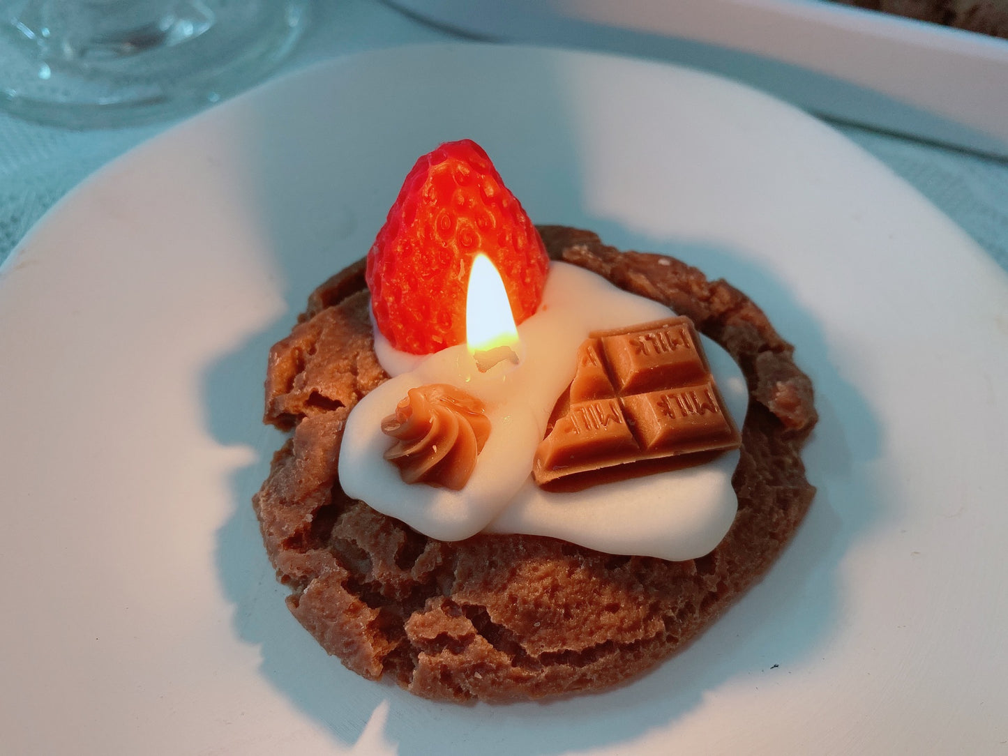 Small dessert with whipped cream, a strawberry, and chocolate pieces on a white plate. Chocolate desserts with whipped cream and raspberries  Handmade Strawberry Cake Aromatic Candle Decoration.