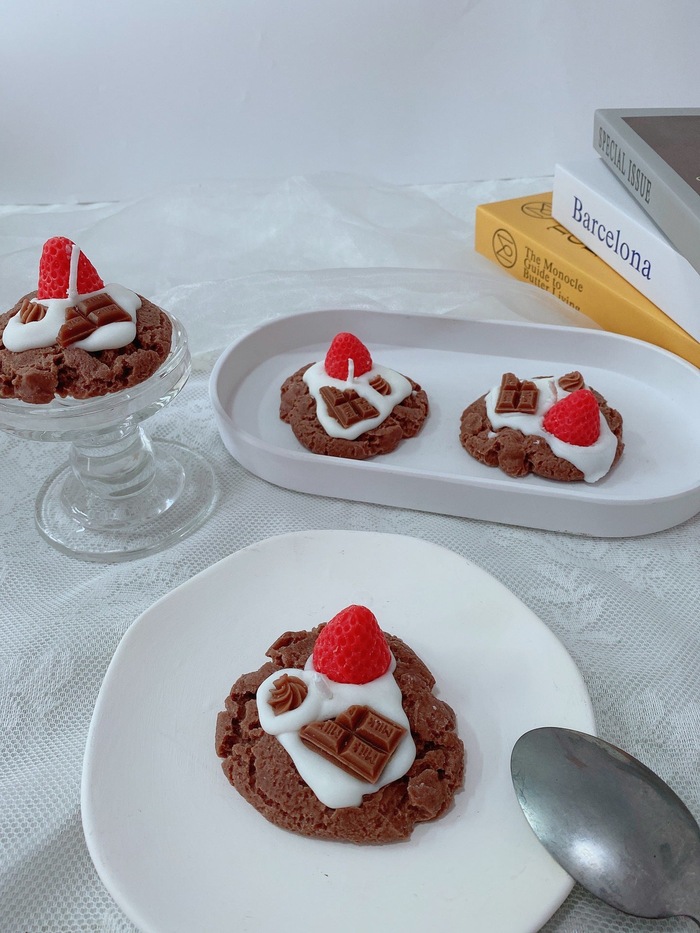 Chocolate cookies with white frosting and red berries on a white plate with a spoon. Chocolate desserts with whipped cream and raspberries on a white tablecloth. Handmade Strawberry Cake Aromatic Candle Decoration. Chocolate cookies with whipped cream and raspberries on a white plate. Indulge your senses with this delightful handmade strawberry cake aromatic candle! Crafted from eco-friendly soybean wax, this charming sector-shaped beauty fills your space with a sweet, bakery