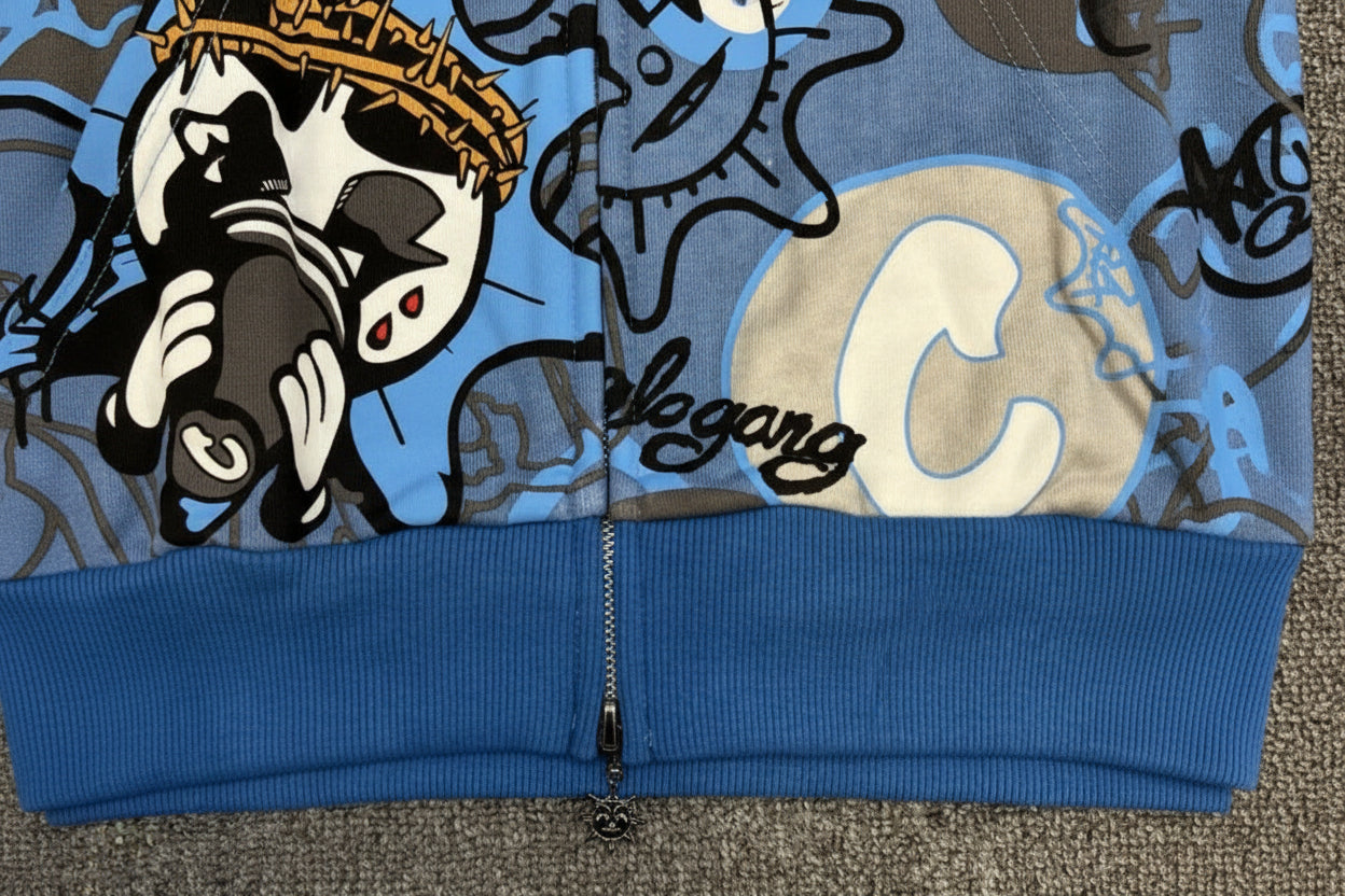 Close-up of a blue hoodie with cartoon character design and text on a gray surface.