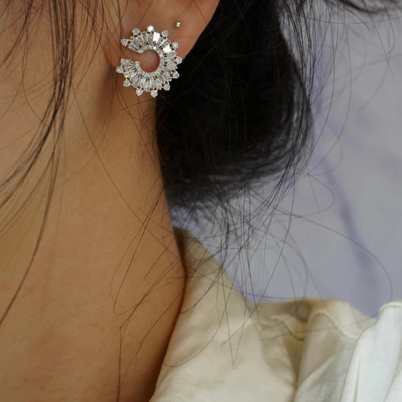 Close-up of a person wearing a 18k white gold earrings with a blurred background