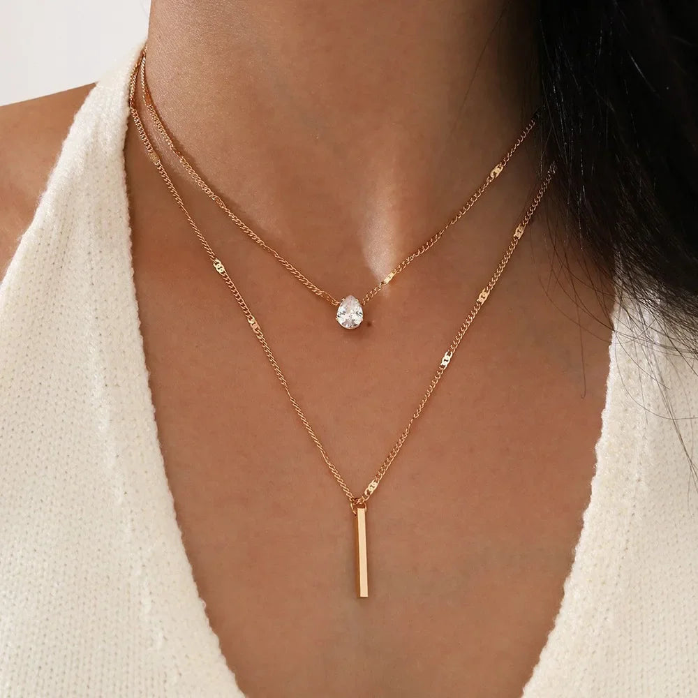 Close-up of a person wearing two gold necklaces with a white background