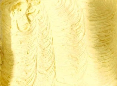 Close-up of creamy yellow substance Yellow shea butter in a container on a marble surface with candles and plants. bestseller whipped mango smell good shea butter moisturizer