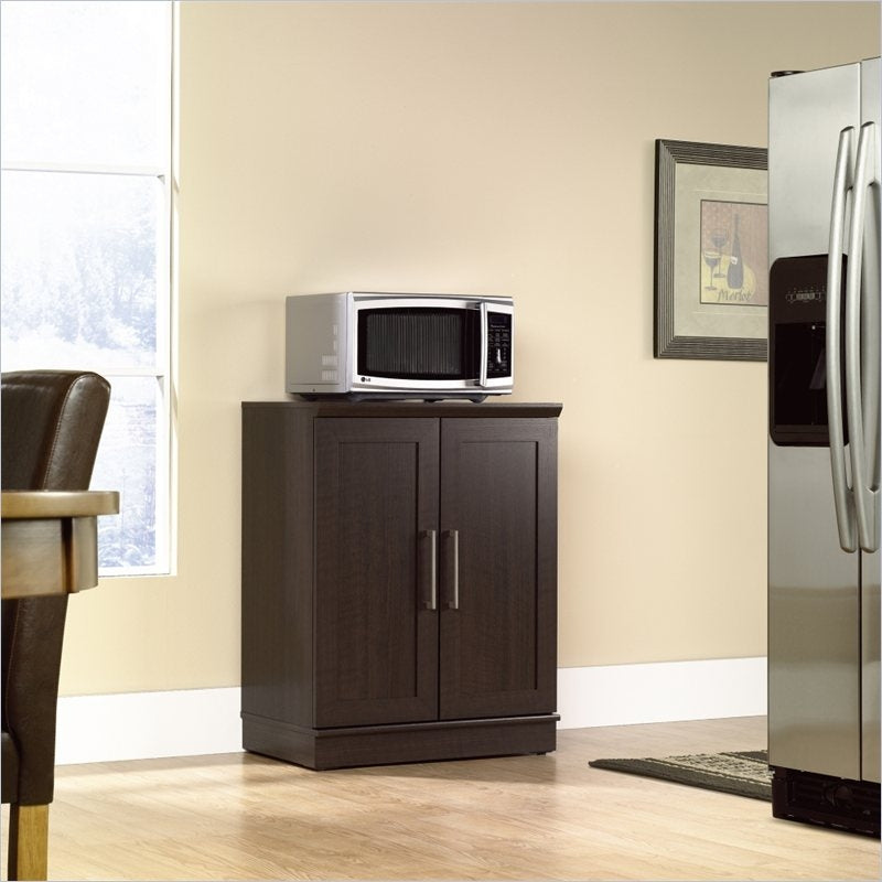 Wooden cabinet with a microwave on top in a kitchen setting.