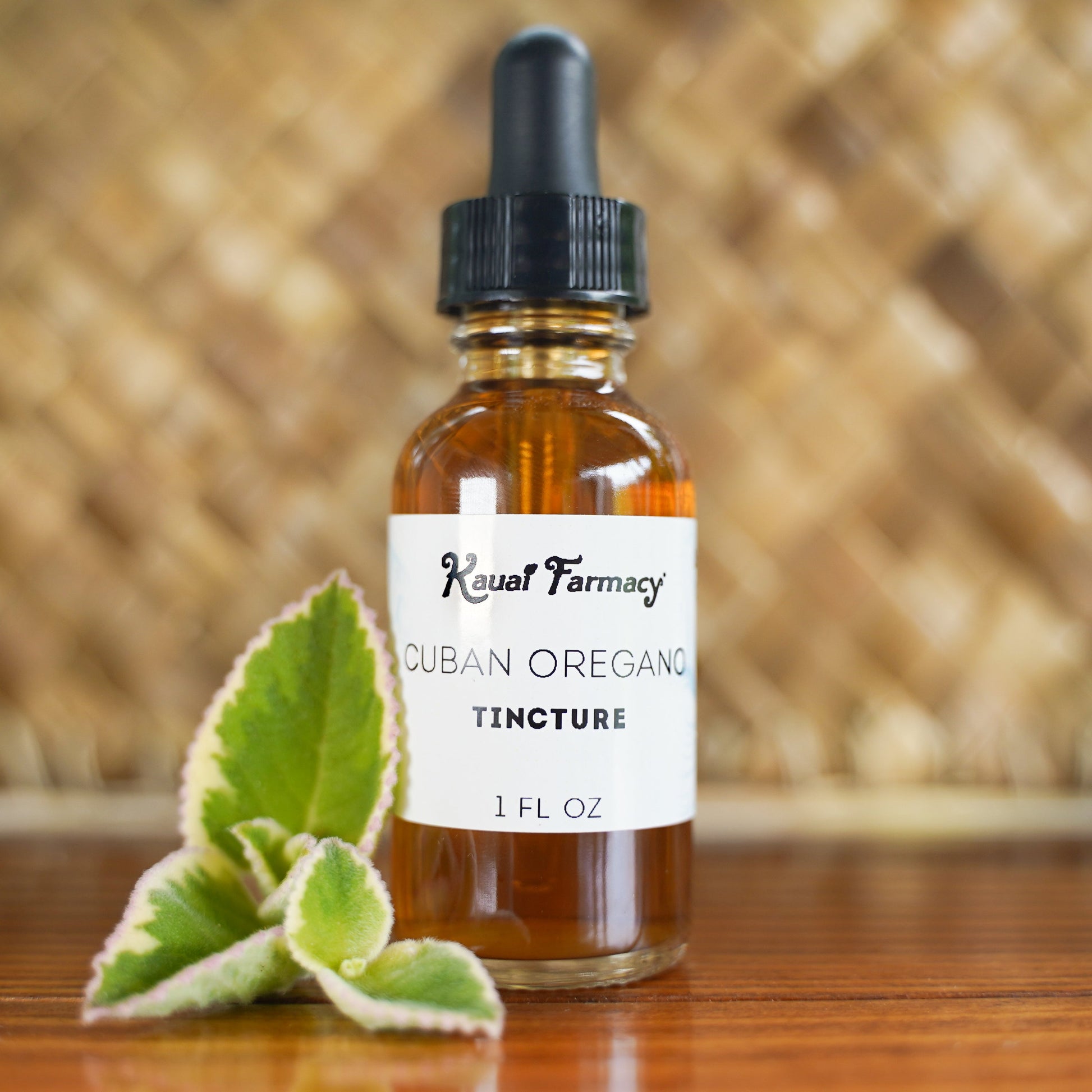 Bottle of Cuban Oregano Tincture from Koval Farmacy with leaves on a wooden surface.