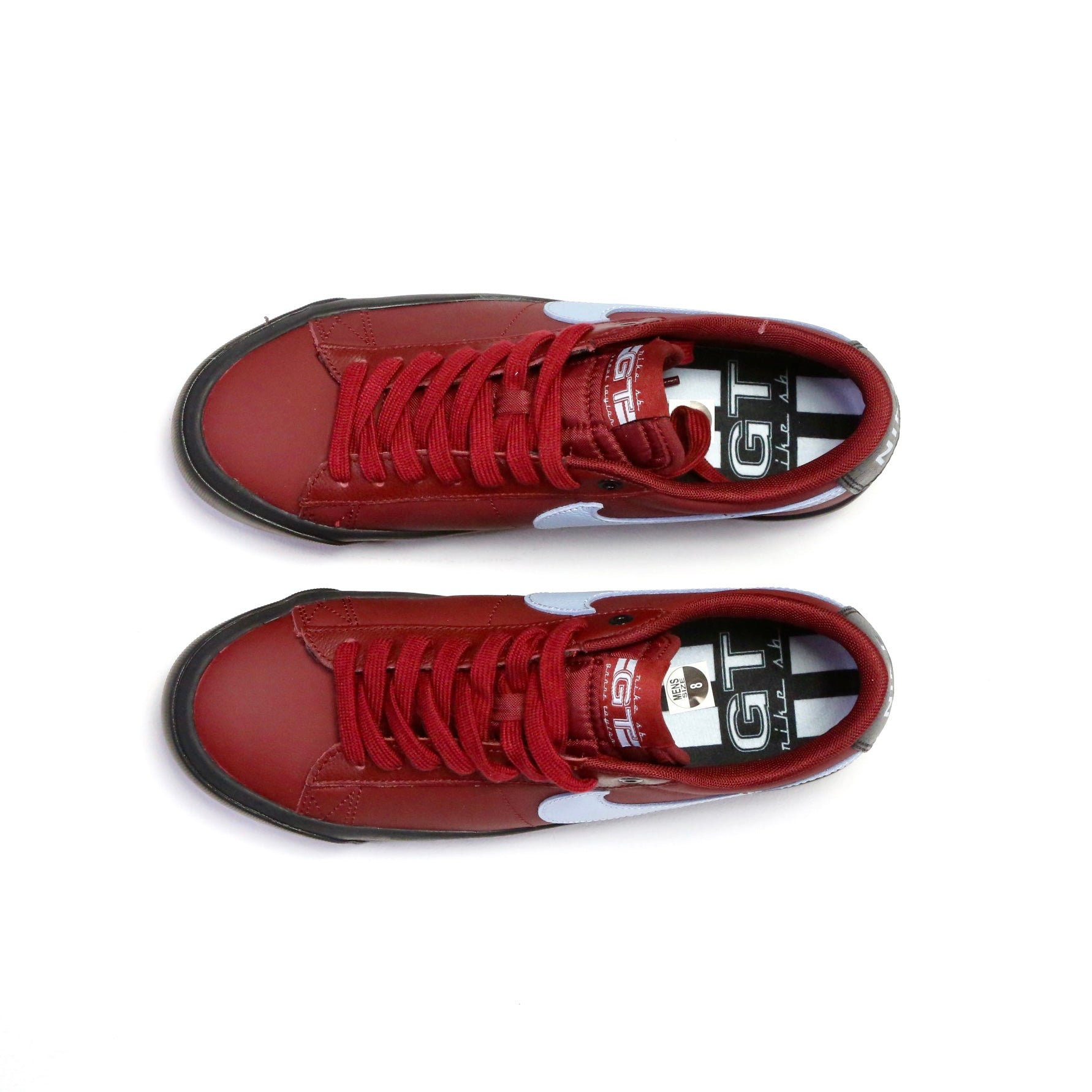 A pair of red low-top sneakers shown from a top-down view on a plain white background. The shoes feature red laces, a black outsole, and a white and black logo on the side and tongue. Nike SB Blazer Low Pro GT DV1226-600