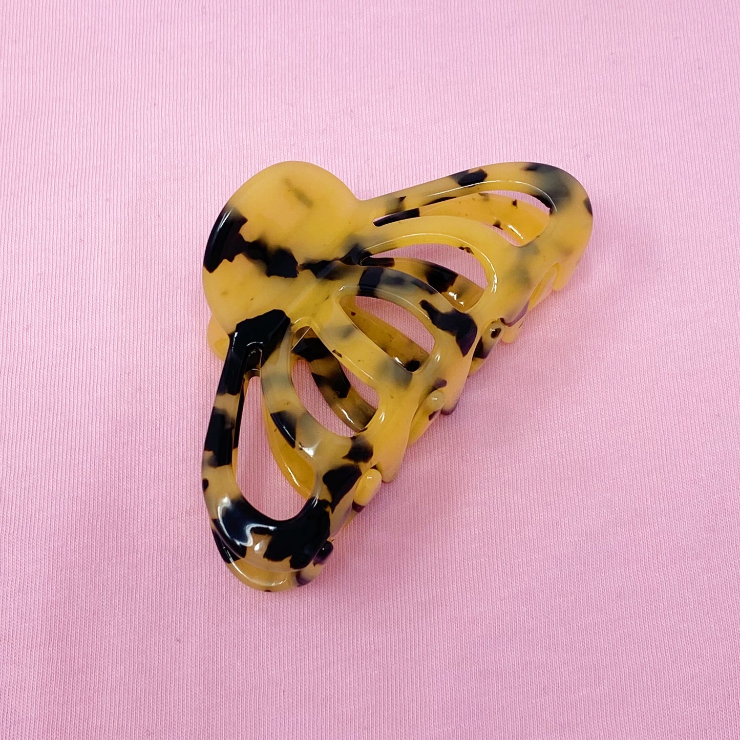 Yellow and black tortoiseshell hair clip on a pink background