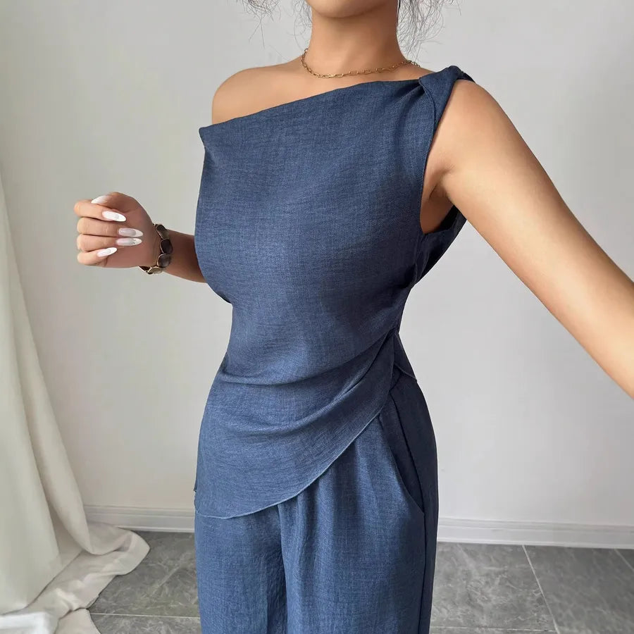 Elegant solid color women's polyester pants co-ord set with asymmetric one-shoulder sleeveless top, zipper closure, matching wide-leg pants, pocket detail, casual office and summer fashion outfit in blue.