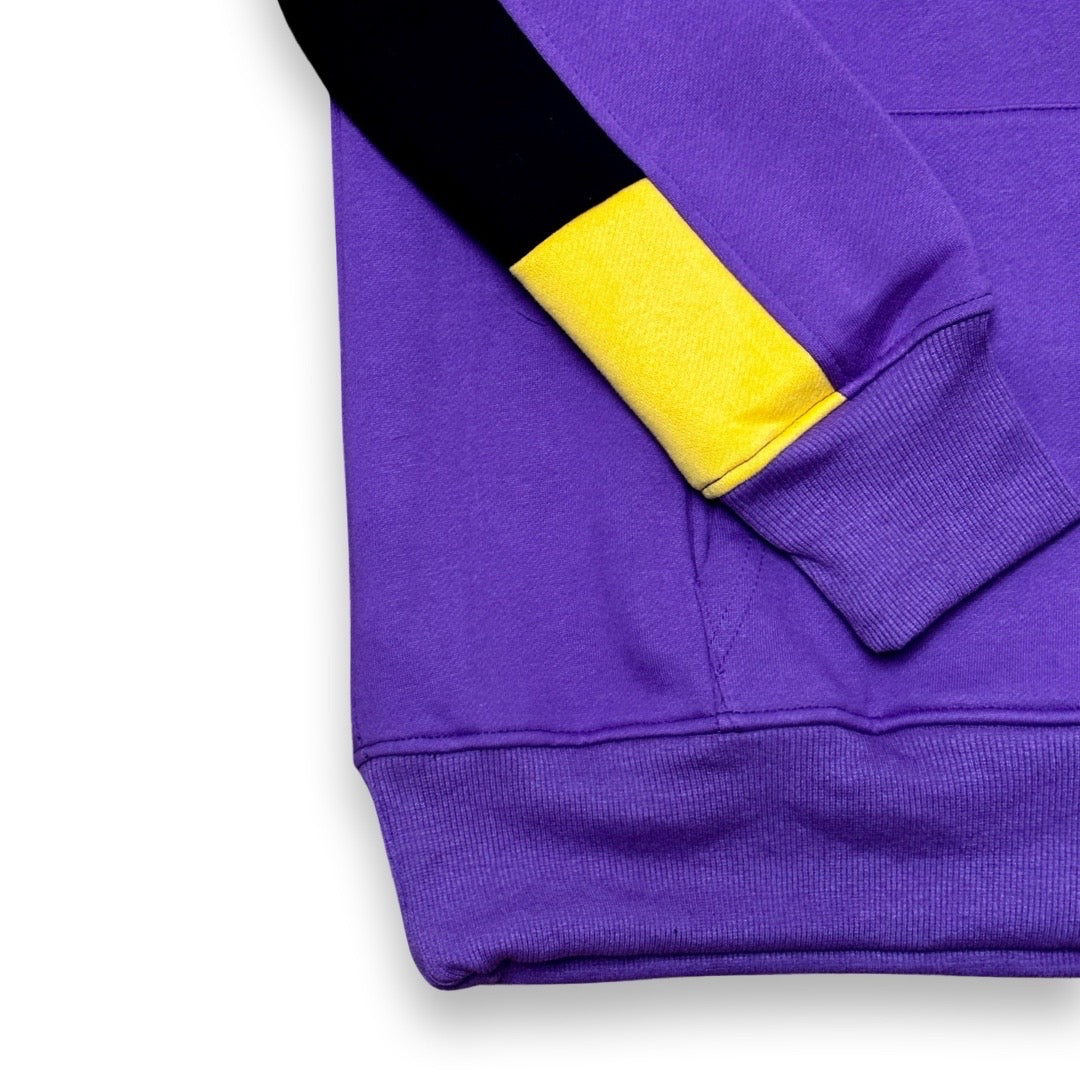 Close-up of a purple sweatshirt sleeve with a black upper section and a bright yellow cuff, shown on a white background.