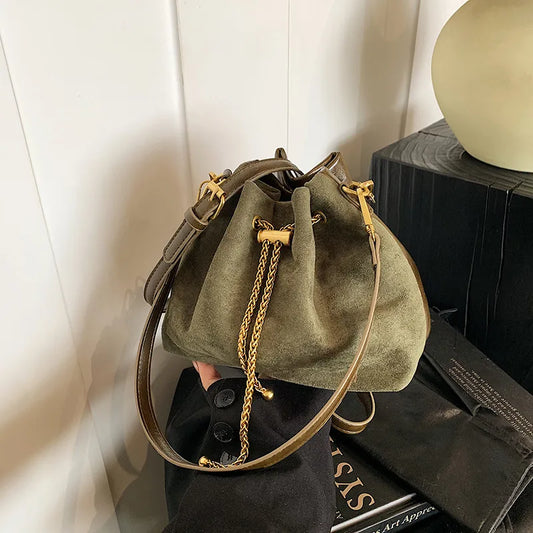 Olive green frosted bucket handbag with a soft suede-like finish, gold chain drawstring accents, and an adjustable PU leather shoulder strap, displayed in hand against a neutral indoor background. Women's mini crossbody purse with a stylish retro design for everyday use.
