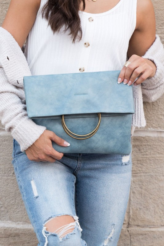 Women's slate blue fold-over clutch purse with antique bronze O-ring handle, envelope silhouette, and soft faux leather construction. Fashionable statement handbag featuring a fold-over flap closure and spacious interior, perfect for weddings, evening events, cocktail parties, date nights, vacations, brunch, work, and everyday wear. Chic designer-inspired blue clutch bag combining elegance, functionality, and contemporary style.