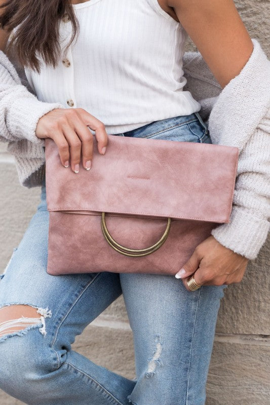 Women's blush pink fold-over clutch purse with antique bronze O-ring handle, envelope silhouette, and soft faux suede-inspired texture. Chic statement handbag featuring a fold-over flap closure and roomy interior, ideal for weddings, bridal showers, evening events, cocktail parties, date nights, vacations, brunch, and everyday wear. Elegant designer-inspired blush pink clutch bag blending sophistication, functionality, and contemporary style.