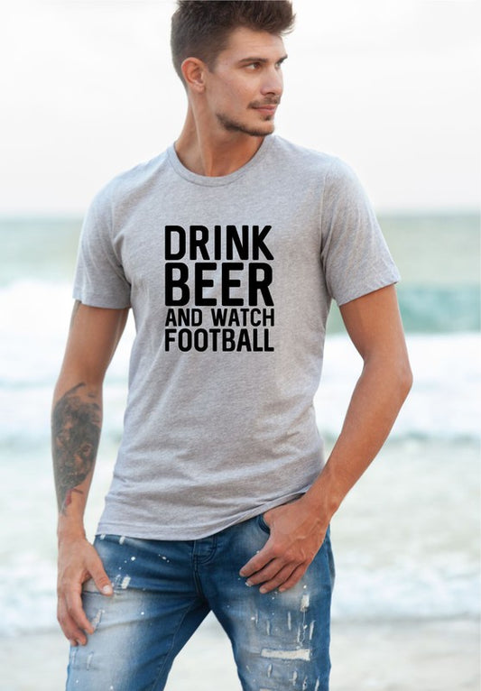 Man wearing a gray t-shirt with 'Drink Beer and Watch Football' text on a beach.
