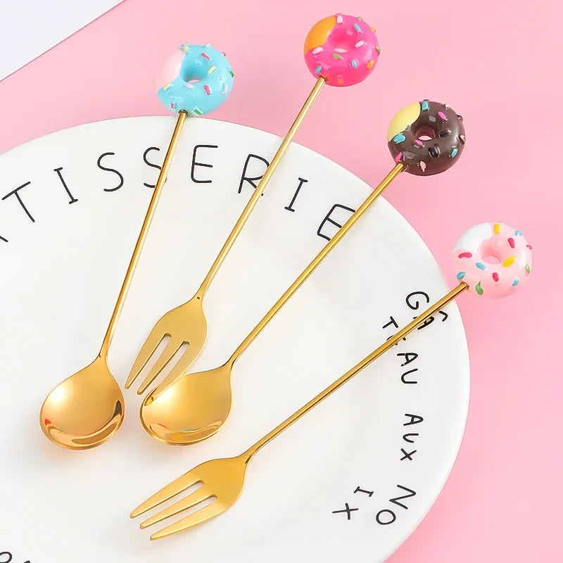 Gold dessert spoons with colorful donut ends on a white plate with black text against a pink background. Gold-colored spoons and forks with colorful donut-shaped ends on a pink background teaspoons stirring spoons dessert fork dessert spoon mini utensils miniature fork and spoon set. Cute Donut Scooping Spoon + Fork (Stainless Steel Stirring Spoons Dessert Utensils)