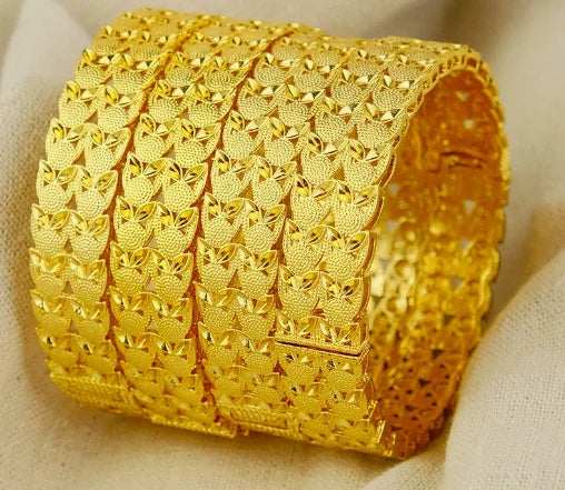 Gold bracelet with intricate design on a beige fabric background