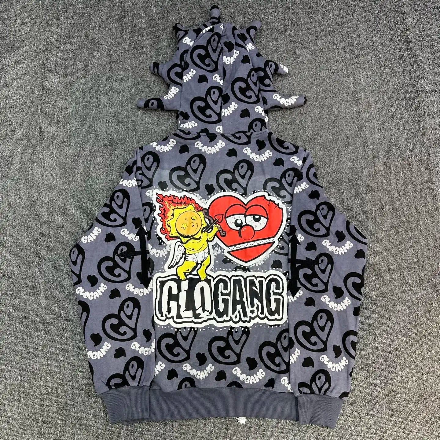 Gray hoodie with black heart patterns and colorful graphic design on a gray surface