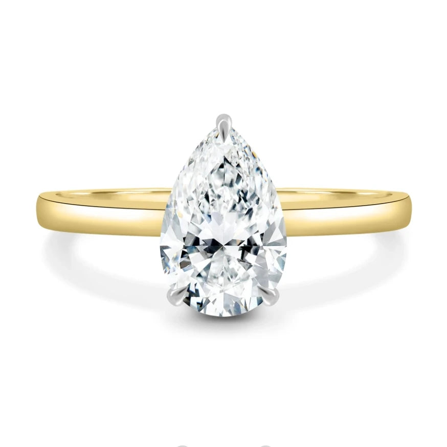 Gold ring with a pear-shaped diamond on a white background