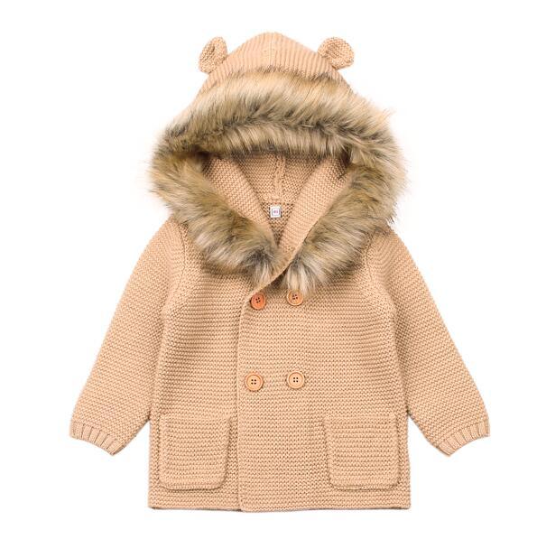 Beige knitted coat with fur hood on a white background