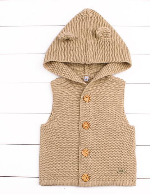 Beige knitted vest with hood on a white wooden background