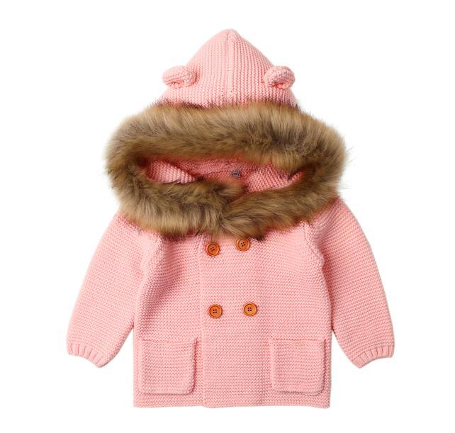Pink knitted jacket with fur hood on a white background