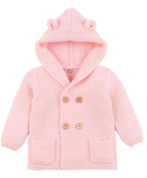 Pink knitted baby coat with hood on a white background