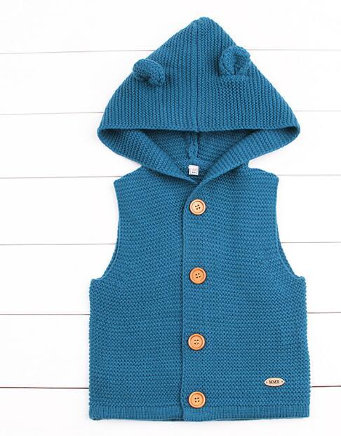 Blue knitted vest with buttons on a white wooden background