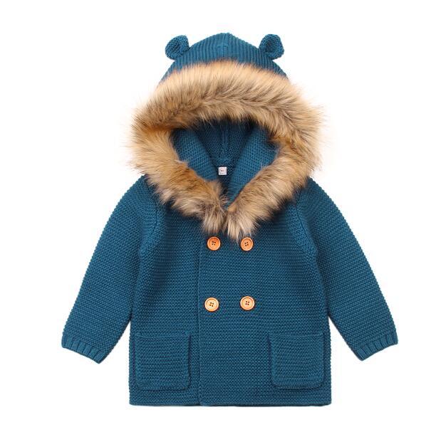 Blue knitted coat with fur hood on a white background