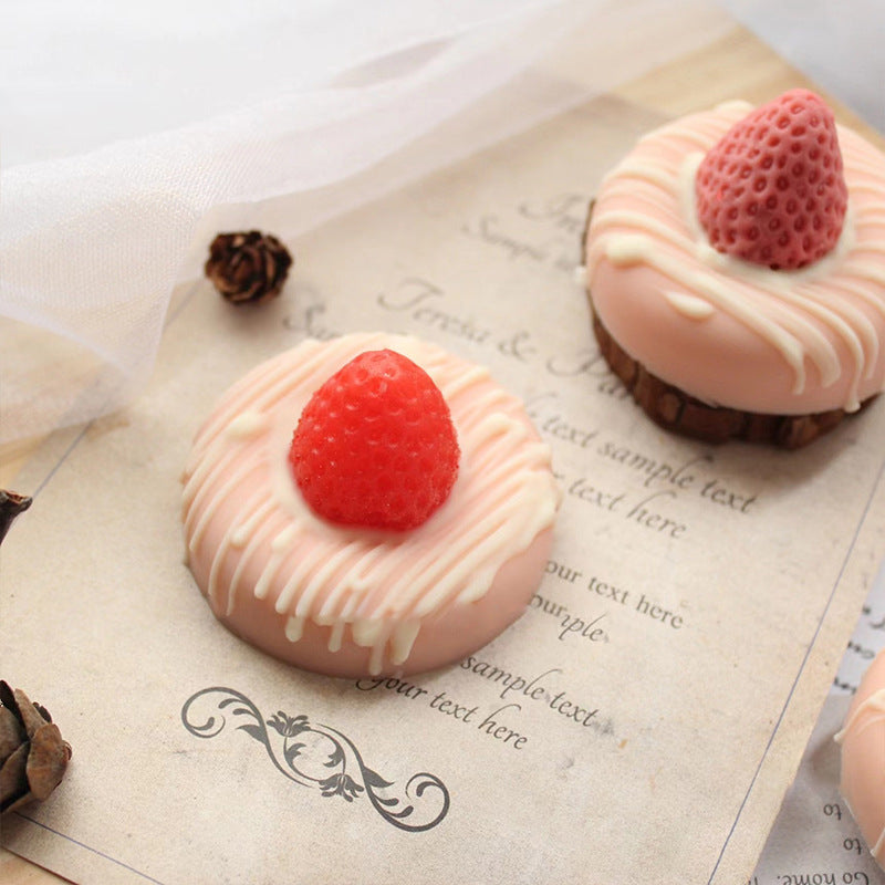 Two pastries with pink glaze and red berries on a textured paper background