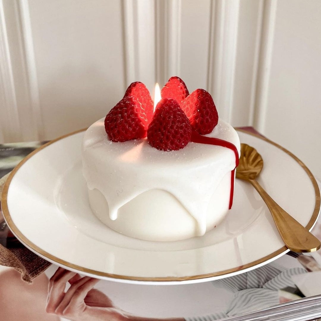 Small white cake with strawberries on a decorative plate. Handmade Strawberry Cake Shaped Candle Soy Wax Aromatherapy