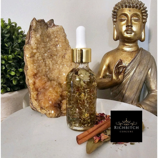 Glass dropper bottle with gold cap on a table with a crystal, cinnamon stick, and Buddha statue. High John Oil - Luxury Hoodoo Conjure Oil for Power, Overcoming Obstacles & Victory
