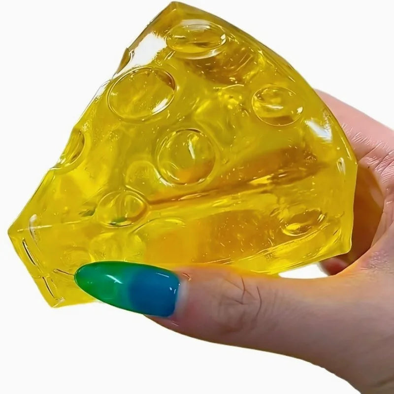 Hand holding a translucent yellow cheese-shaped squishy stress toy with realistic bubble-like indentations against a white background.