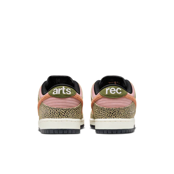 A pair of low-top sneakers shown from the back, featuring a pink and beige speckled pattern, olive green heel tabs with 'arts' and 'rec' in white text, and black soles. Nike SB Arts & Rec Dunk Low