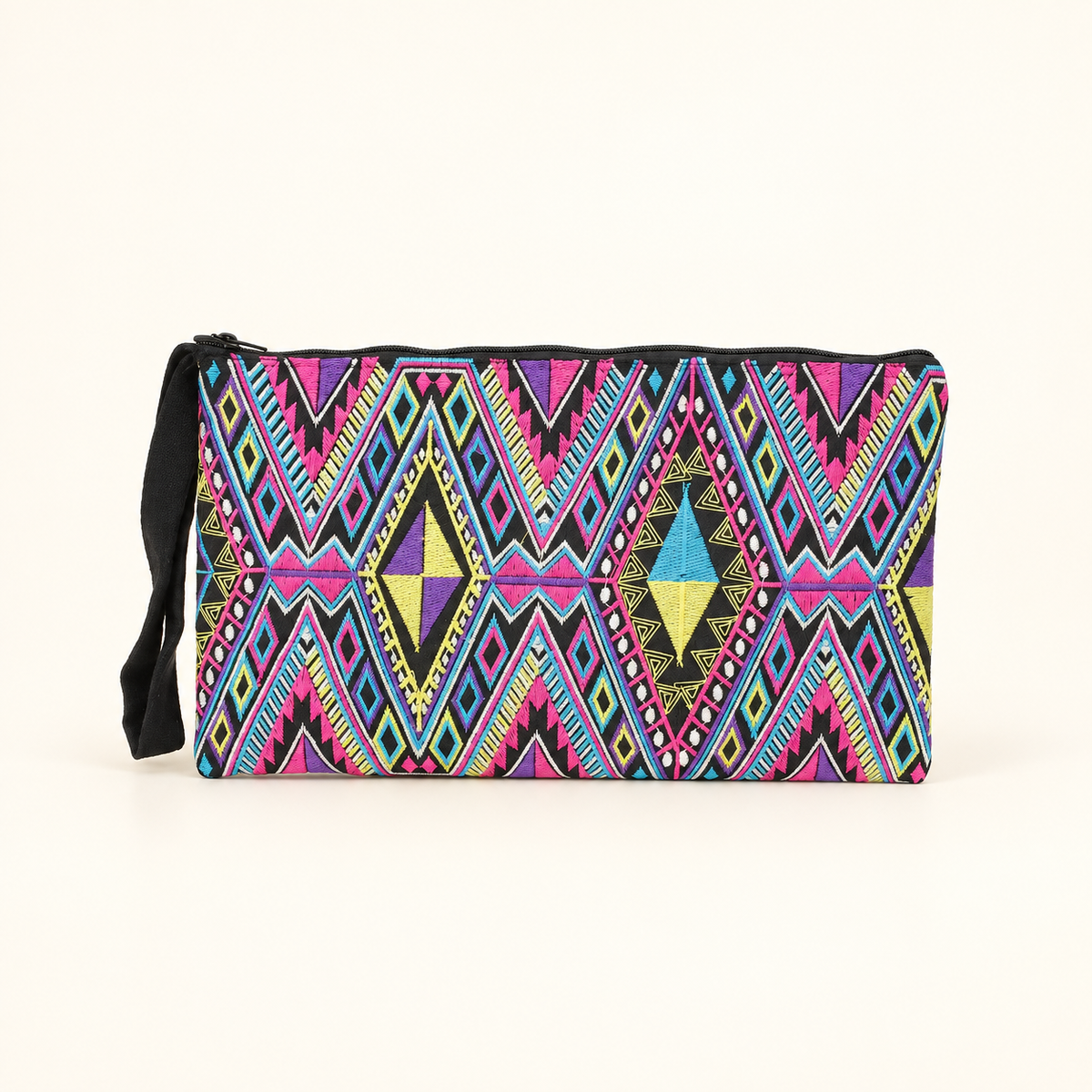 A rectangular zippered clutch bag with a vibrant, multicolor geometric tribal pattern featuring pink, blue, yellow, and black, complete with a black wristlet strap, set against a plain off-white background.