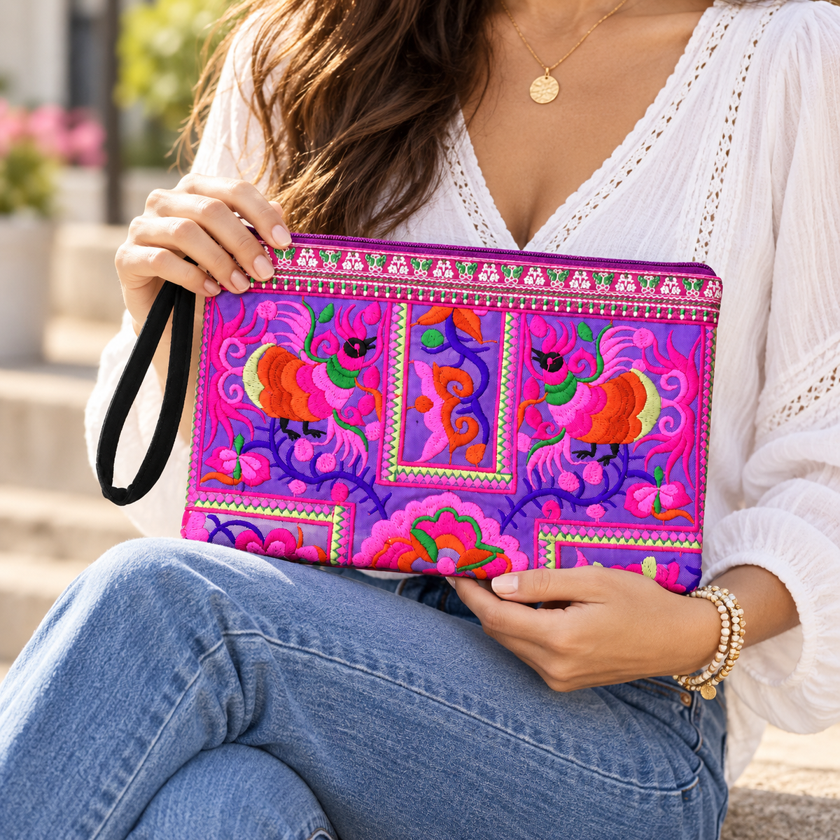 Handmade Sarita wristlet clutch featuring vibrant, Hmong-inspired embroidery on artisanal fabric. This ethically crafted accessory from Northern Thailand perfectly blends bold, traditional patterns with modern utility, offering a spacious, fully-lined interior ideal for your daily essentials. Each unique piece is finished with a convenient wrist strap, making it the perfect grab-and-go companion for any occasion