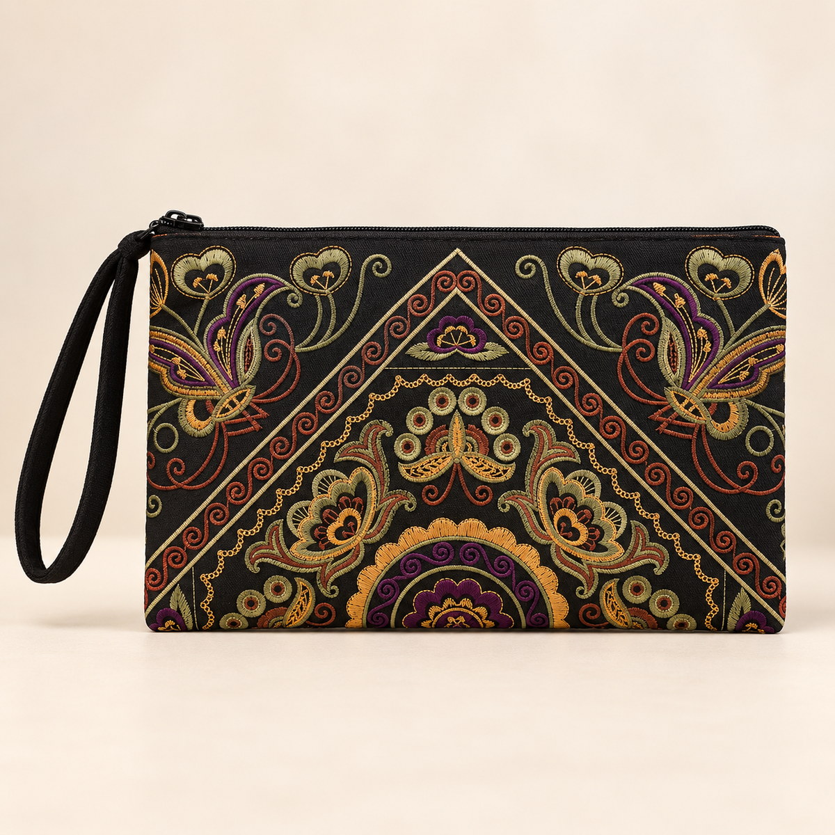 A black zippered wristlet clutch with a detailed, colorful paisley and floral pattern in gold, purple, and red, featuring a black wrist strap on the left.