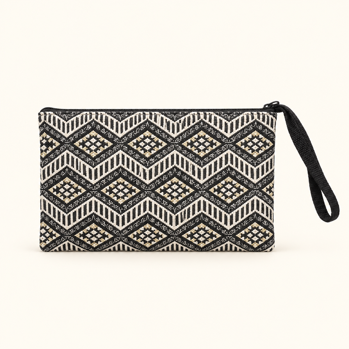 A rectangular zippered clutch or wristlet pouch with a black, white, and beige geometric diamond pattern, featuring a black wrist strap on the right side, set against a solid off-white background.