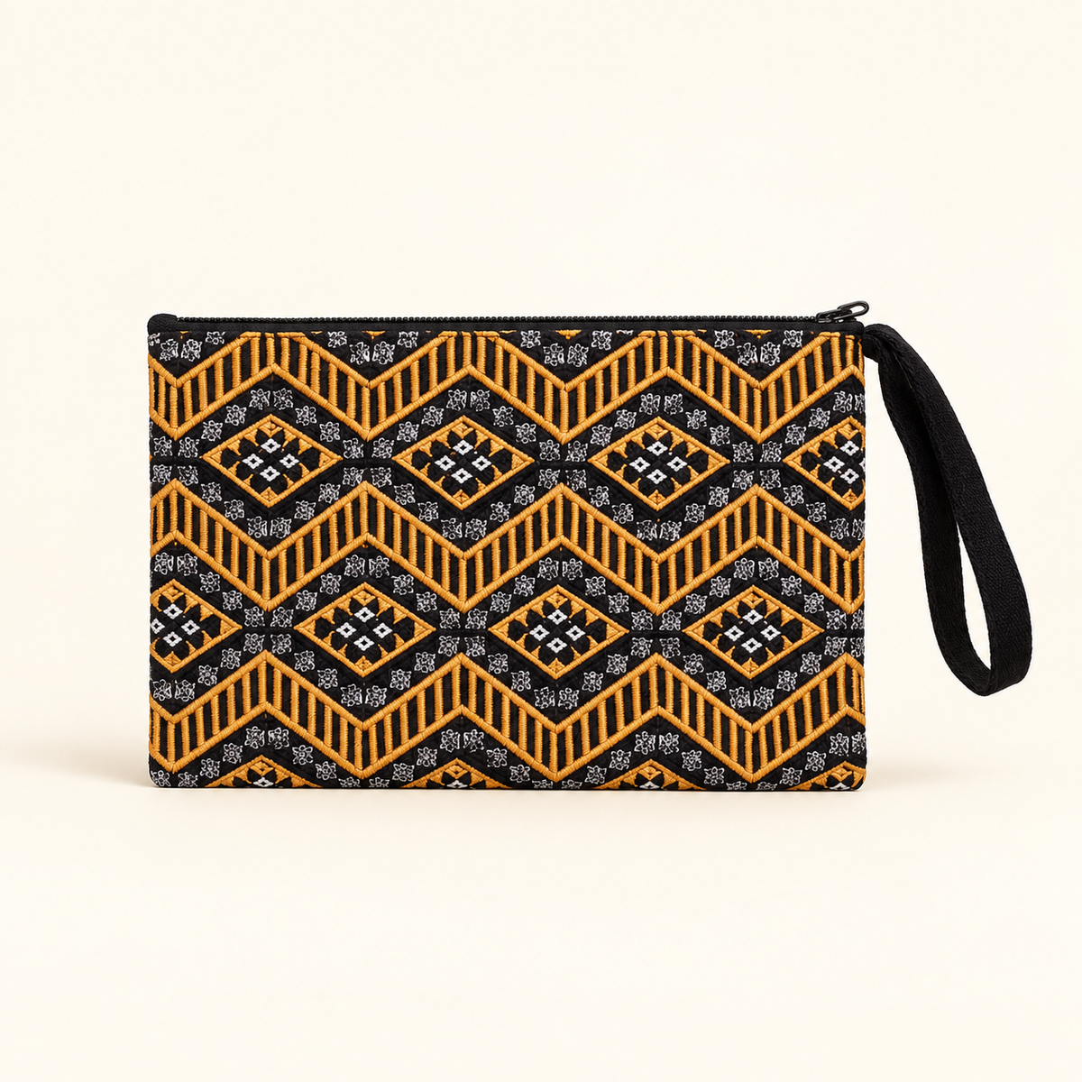 A zippered wristlet clutch with a black and orange geometric pattern and a black wrist strap, shown on a light cream background.