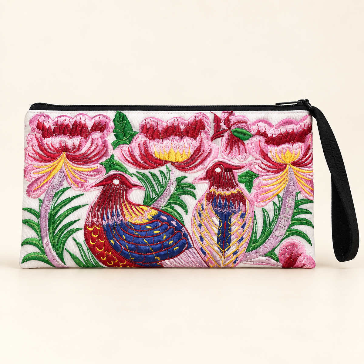 A rectangular embroidered wristlet clutch with a black zipper and wrist strap, featuring a vibrant floral and bird pattern on a white base.