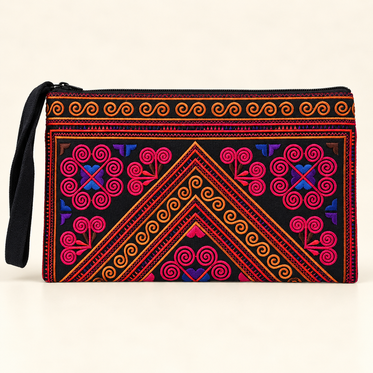 A black zippered clutch bag with vibrant, colorful embroidered geometric and floral patterns in pink, orange, red, and blue, featuring a black wrist strap on a light beige background.