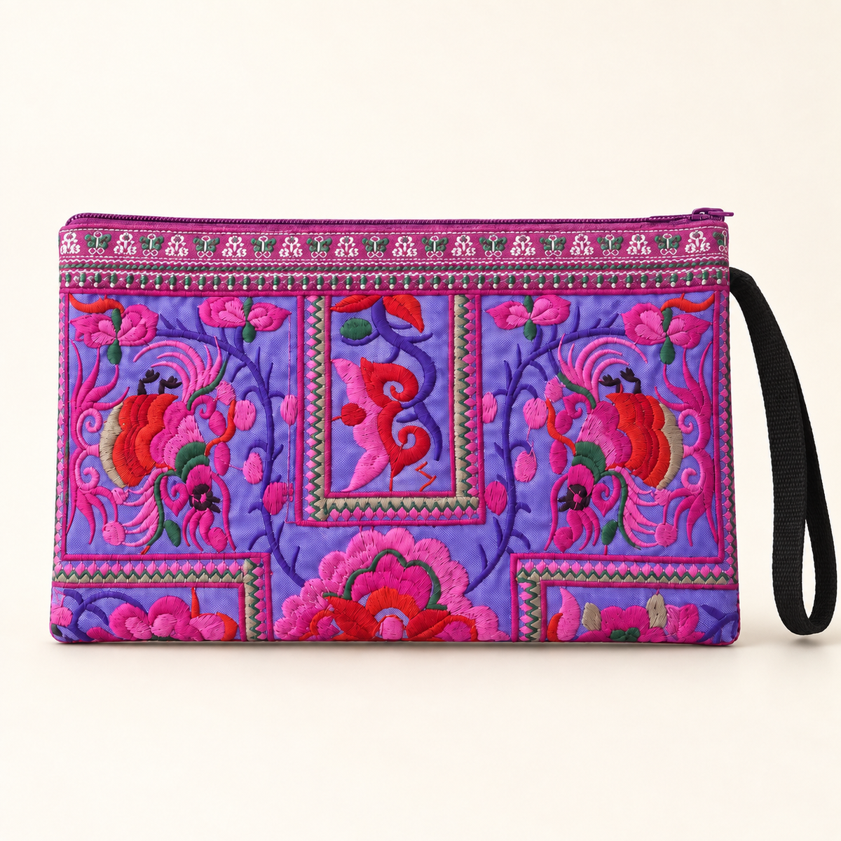 A purple and pink embroidered clutch bag with a black wrist strap, featuring vibrant floral and bird motifs on a light beige background.