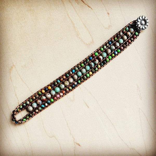 Layer genuine Impression Jasper stones in a woven design that brings earthy elegance to any look. This multi-colored bracelet features three stacked stone strands creating a textured, artisanal aesthetic. Measuring approximately 1" wide and 9" in length, it's the perfect accessory to mix and match with your everyday style. Versatile, natural, and effortlessly chic.