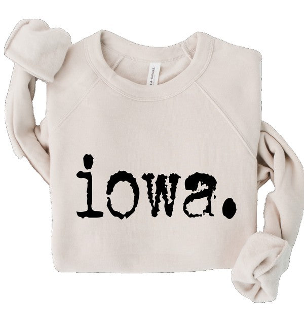 Iowa Premium Bella Canvas sweatshirt featuring bold black "iowa." typography on a soft cream fleece crewneck, folded for display. Comfortable unisex pullover available in plus sizes 2XL and 3XL, perfect for Iowa pride, casual wear, gifting, and year-round layering.