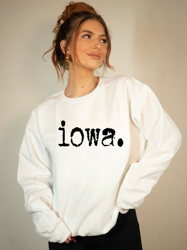 Woman modeling a white Bella+Canvas fleece sweatshirt featuring a distressed black "Iowa." graphic, plus size unisex crewneck casual state pride apparel.